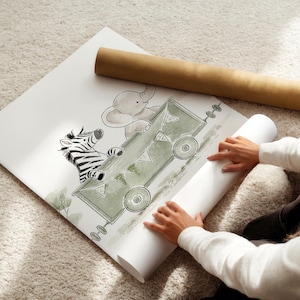 May include: A white poster featuring a green illustrated train carriage carrying a zebra and an elephant. The train car is decorated with small triangular bunting flags and has circular wheels. The artwork is rendered in a soft, sketch-like style.