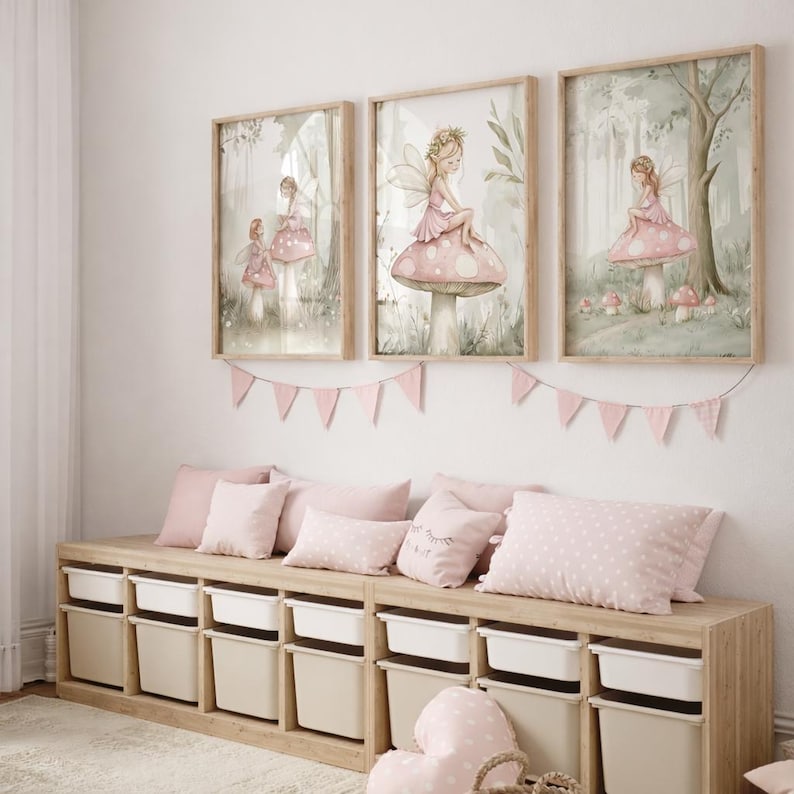 May include: Three framed watercolor prints featuring fairies in a forest setting. The fairies are depicted in pink dresses, sitting on mushrooms. A pink banner hangs below the prints, and a wooden storage bench with pink pillows and storage bins is below.