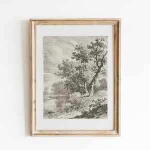 May include: A black and white print of a landscape scene with a large tree in the foreground and a river in the background. The print is framed in a light wood frame.