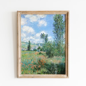 Puede incluir: Una pintura enmarcada que representa un paisaje con un campo de flores silvestres, un pequeño pueblo en la distancia y un grupo de árboles en primer plano. El cielo es azul con nubes blancas.