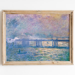 以下が含まれることがあります： 水上の橋の印象派絵画、明るい木材で額装されています。 この作品は、青、紫、金色のパレットを特徴とし、筆致が見えます。 小さなボートが水上にあります。 アーティストのサインは左下にあります。