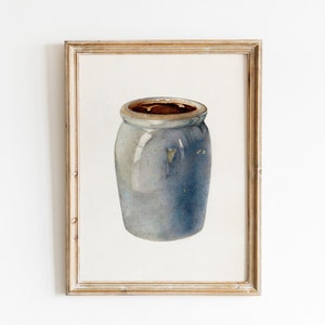 May include: A framed watercolor painting of a blue and white ceramic jar with a brown rim.