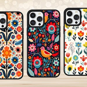 May include: Three phone cases with floral designs. The cases have black borders and feature colourful patterns of flowers and birds. The designs include red, blue, orange, and yellow on cream and black backgrounds.