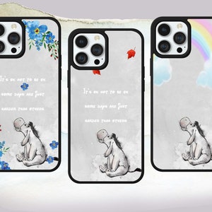 May include: Three phone cases with different designs. The first case features a blue floral design with a quote about hard days. The second case has a red leaf design and the same quote. The third case has a rainbow and clouds design with a cartoon donkey.