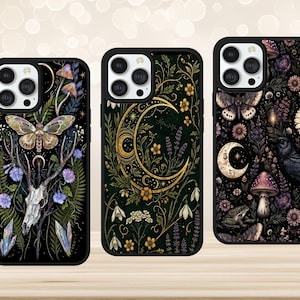 May include: Three black smartphone cases featuring detailed illustrations. The left case shows a moth, deer skull, and ferns. The centre case displays a golden crescent moon with flowers. The right case features a raven, mushrooms, and a moth.