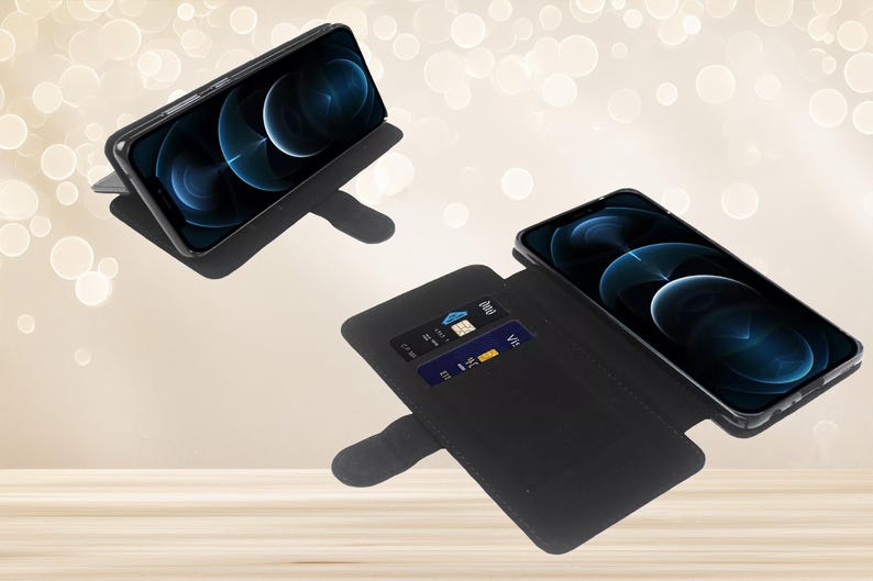 May include: Two black smartphone wallet cases shown in different positions. One case is propped up in a landscape viewing angle, while the other is open, displaying a smartphone screen and two interior card slots containing credit cards.