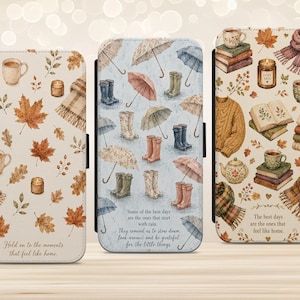 May include: Three rectangular phone cases featuring autumn-themed illustrations. The left case shows maple leaves, mugs, and candles with the text 'Hold on to the moments that feel like home.' The centre case displays rain boots and umbrellas with the text 'Some of the best days are the ones that start with rain. They remind us to slow down, look around, and be grateful for the little things.' The right case features books, sweaters, scarves, and mugs with the text 'The best days are the ones that feel like home.'
