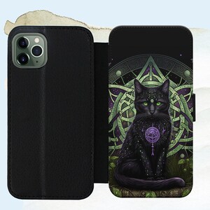 Puede incluir: Funda de tel&eacute;fono negra con un dise&ntilde;o de nudo celta verde y morado y un gato negro con ojos verdes en el centro. El gato sostiene un orbe morado con una estrella en su interior.