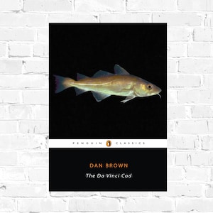 May include: A Penguin Classics paperback book cover featuring a black and white illustration of a fish and the text "DAN BROWN The Da Vinci Cod"