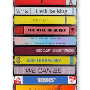 Może przedstawiać: Stos ośmiu kaset magnetofonowych z kolorowymi etykietami i tekstem. Tekst na etykietach brzmi: "I", "I will be king", "and you", "YOU WILL BE QUEEN", "THOUGH NOTHING", "WILL DRIVE THEM AWAY", "WE CAN BEAT THEM", "JUST FOR ONE DAY", "WE CAN BE", "HEROES", "JUST FOR ONE DAY".