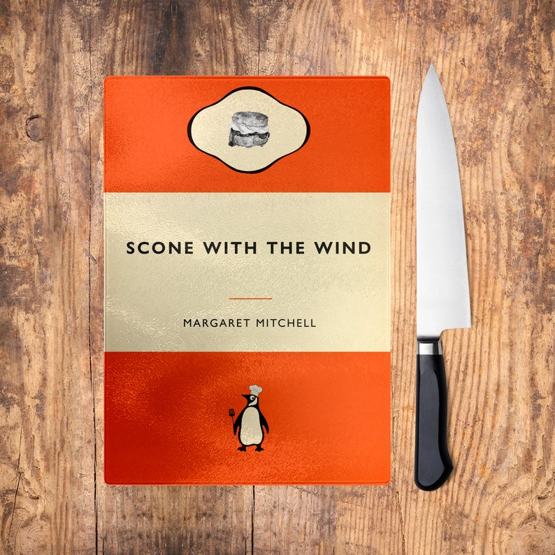 May include: A red and white cutting board with the text "Scone With The Wind" and "Margaret Mitchell" printed on it. The board features a penguin illustration and a scone icon.