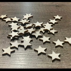 Könnte beinhalten: Ein Haufen weißer Holzsterne, die auf einer Holzoberfläche verstreut sind.