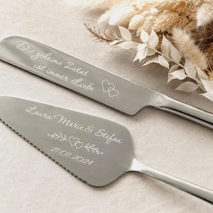 Può includere: Un set composto da coltello e paletta per torta color argento con incisioni. Il coltello riporta la frase Die geheime Zutat ist immer Liebe e due cuori. La paletta mostra i nomi Laura-Marie & Stefan, un cuore e la data 27.07.2024.