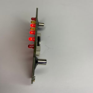 May include: A circuit board with a row of red and yellow LED lights. The board has two metal connectors on the side.