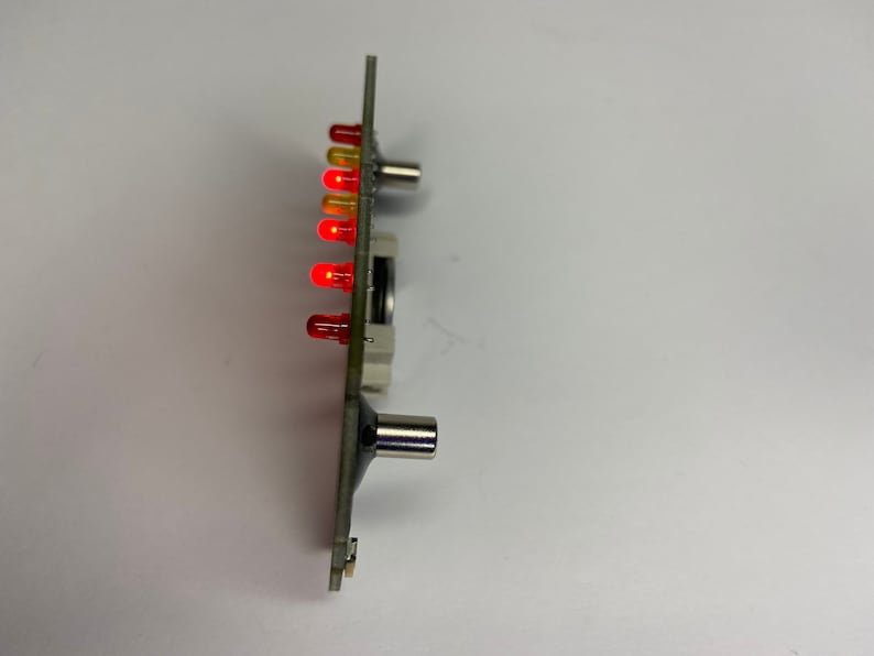 May include: A circuit board with a row of red and yellow LED lights. The board has two metal connectors on the side.