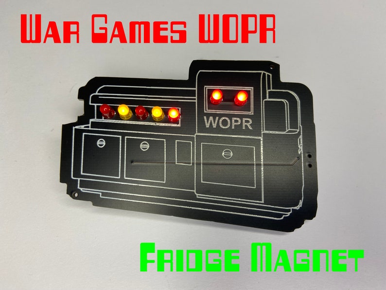 May include: A black WarGames WOPR fridge magnet with red and yellow LED lights. The magnet features a stylized image of the WOPR computer from the movie WarGames.