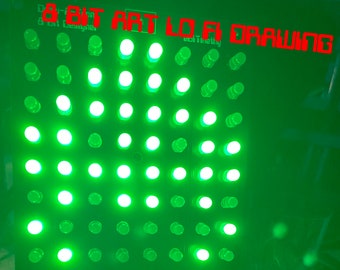 May include: A green LED light grid with 64 lights arranged in an 8x8 grid. The lights are on and forming a pattern. The text "8-BIT ART LO-FI DRAWING" is written in red above the grid.