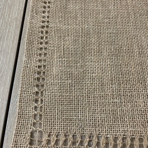 May include: A brown burlap placemat with a decorative stitched border.