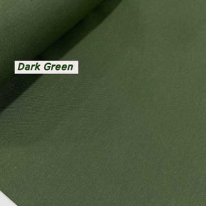 Puede incluir: Muestra de tela verde oscuro. La tela tiene una textura lisa y uniforme.