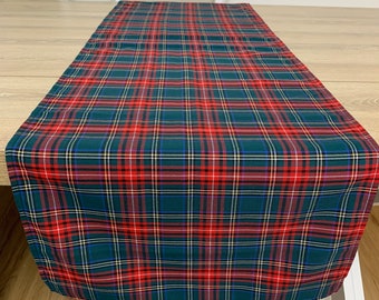 May include: A green, red, and white plaid table runner. The runner has a traditional tartan pattern.