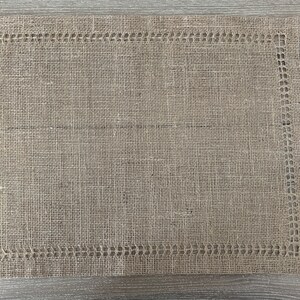 May include: A brown woven placemat with a decorative border. The placemat is made from a natural material and has a rustic look.