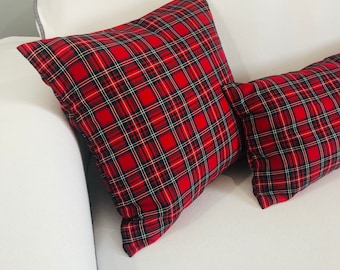 Könnte beinhalten: Zwei rote und schwarze karierten Kissen auf einem weißen Sofa. Die Kissen sind aus weichem, gewebtem Stoff und haben ein klassisches Karomuster.