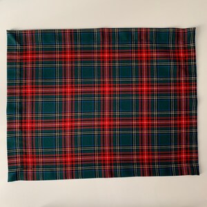 May include: A green, red, and white plaid placemat with a woven texture.