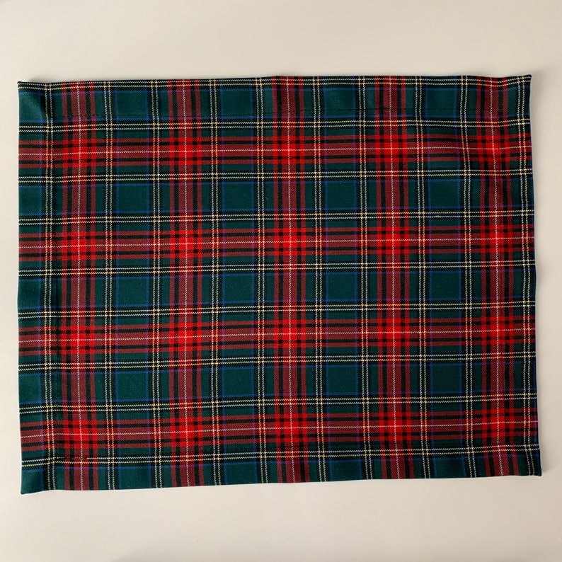 May include: A green, red, and white plaid placemat with a woven texture.