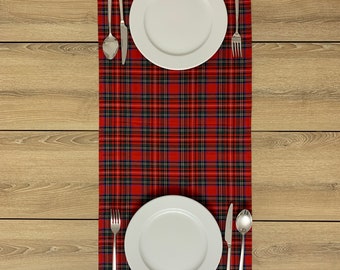 May include: Two white dinner plates with silver cutlery set on a red and black plaid tablecloth.