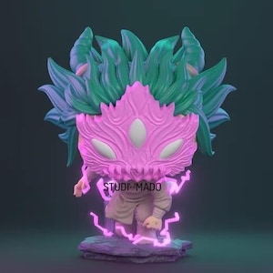 May include: A stylized figurine with a pink mask and green and blue hair-like elements. The figure is wearing a tan outfit and stands on a purple stone base. The text "STUDI MADO" is visible on the figure. Purple energy emanates from the base.