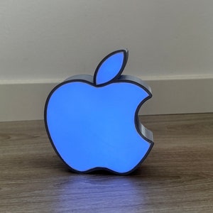 Op de afbeelding: Een blauw verlicht nachtlampje in de vorm van het Apple-logo. Het licht is aan en het logo gloeit.
