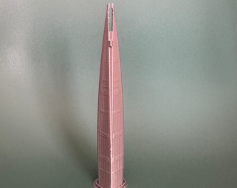 May include: A 3D printed model of a tall, slender building with a pointed top. The model is made of a light brown plastic and has a textured surface.
