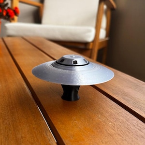 May include: A white ceramic mug with a black handle and the text "But First, Coffee" in a black, handwritten-style font. The mug is on a white surface.