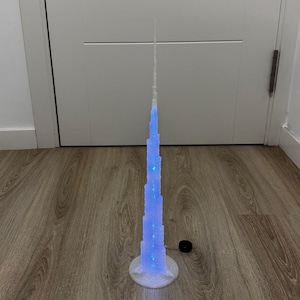 Peut inclure: Maquette lumineuse du Burj Khalifa, réplique détaillée de ce gratte-ciel emblématique. La tour est éclairée de lumières bleues et repose sur une base blanche. Le modèle mesure environ 60 cm de haut.