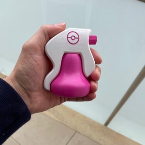 Puede incluir: Una botella de spray de pl&aacute;stico blanca y rosa con un logotipo de Pokeball en el lateral. La botella est&aacute; dise&ntilde;ada para parecerse a un personaje de Pokemon.