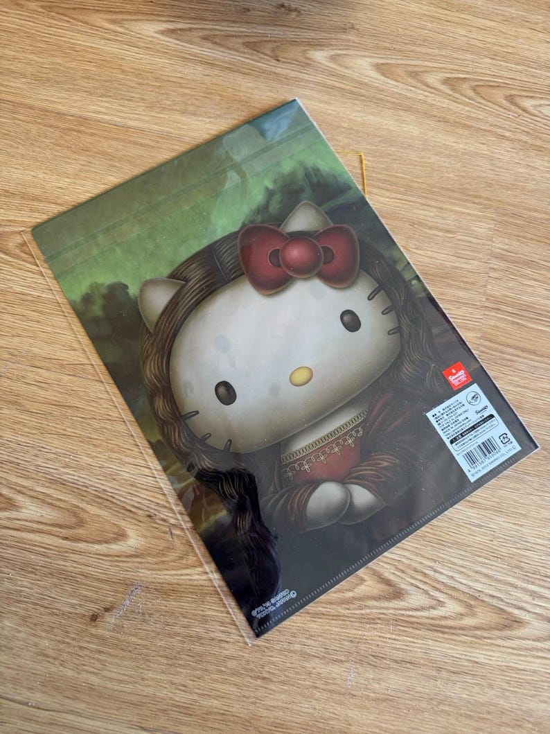 May include: A clear plastic document folder featuring a graphic illustration of the character Hello Kitty styled as the Mona Lisa, complete with long dark hair, a red bow, and a dark dress, set against a green landscape background with text.