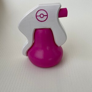 Puede incluir: Una botella de spray de pl&aacute;stico rosa y blanco con un logotipo de Pokeball blanco en la parte superior.
