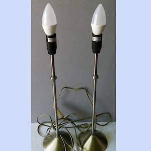 Op de afbeelding: Twee messing tafellampen met witte LED-lampen. De lampen hebben een eenvoudig ontwerp met een ronde voet en een enkele steel.