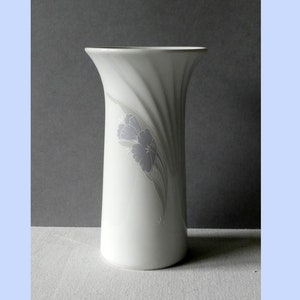 Könnte beinhalten: Weiße Keramikvase mit einem wirbelnden Design und einem grauen Blumenmuster.