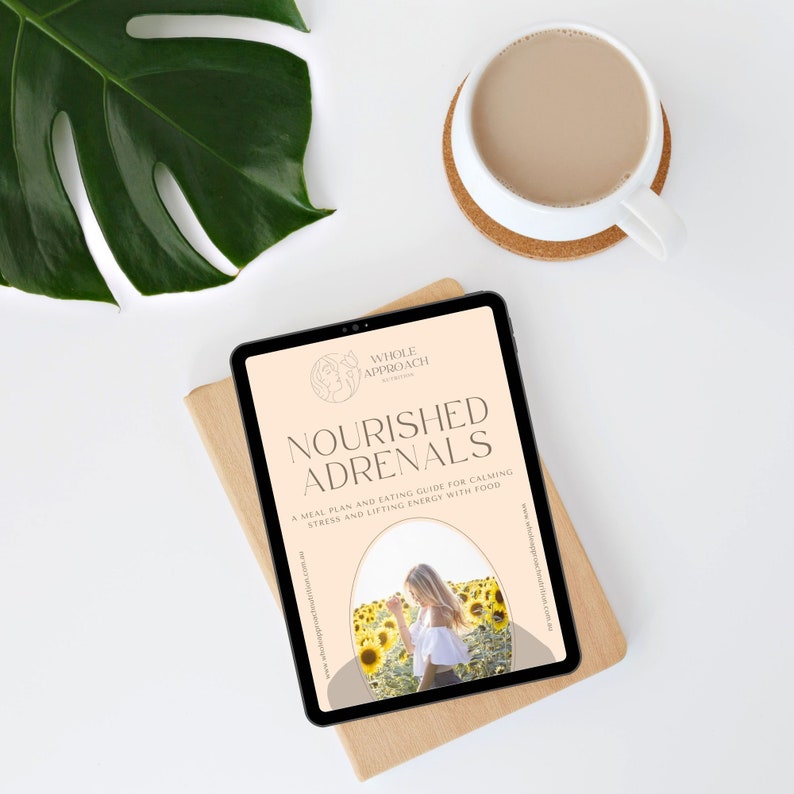 May include: A digital tablet displaying a guide titled "Nourished Adrenals" with a subtitle "A meal plan and eating guide for calming stress and lifting energy with food". The guide features a woman standing in a field of sunflowers.