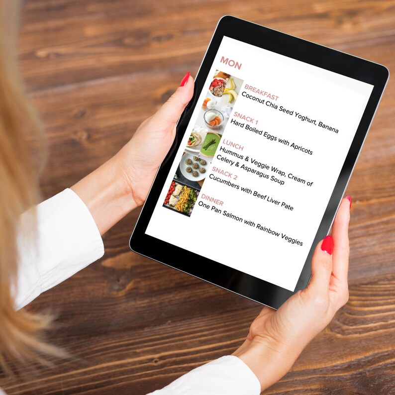 May include: A tablet screen displaying a weekly meal plan for Monday. The plan includes breakfast, snack 1, lunch, snack 2, and dinner. Each meal is listed with a brief description and a small image of the food.