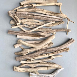 May include: A collection of driftwood sticks in various sizes and shapes, with a natural, light brown color. The sticks are arranged in a random pattern, creating a rustic and organic aesthetic.