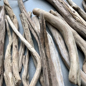 May include: A collection of driftwood sticks in various sizes and shapes, with a light brown and gray color. The sticks are arranged in a random pattern, creating a natural and rustic aesthetic.