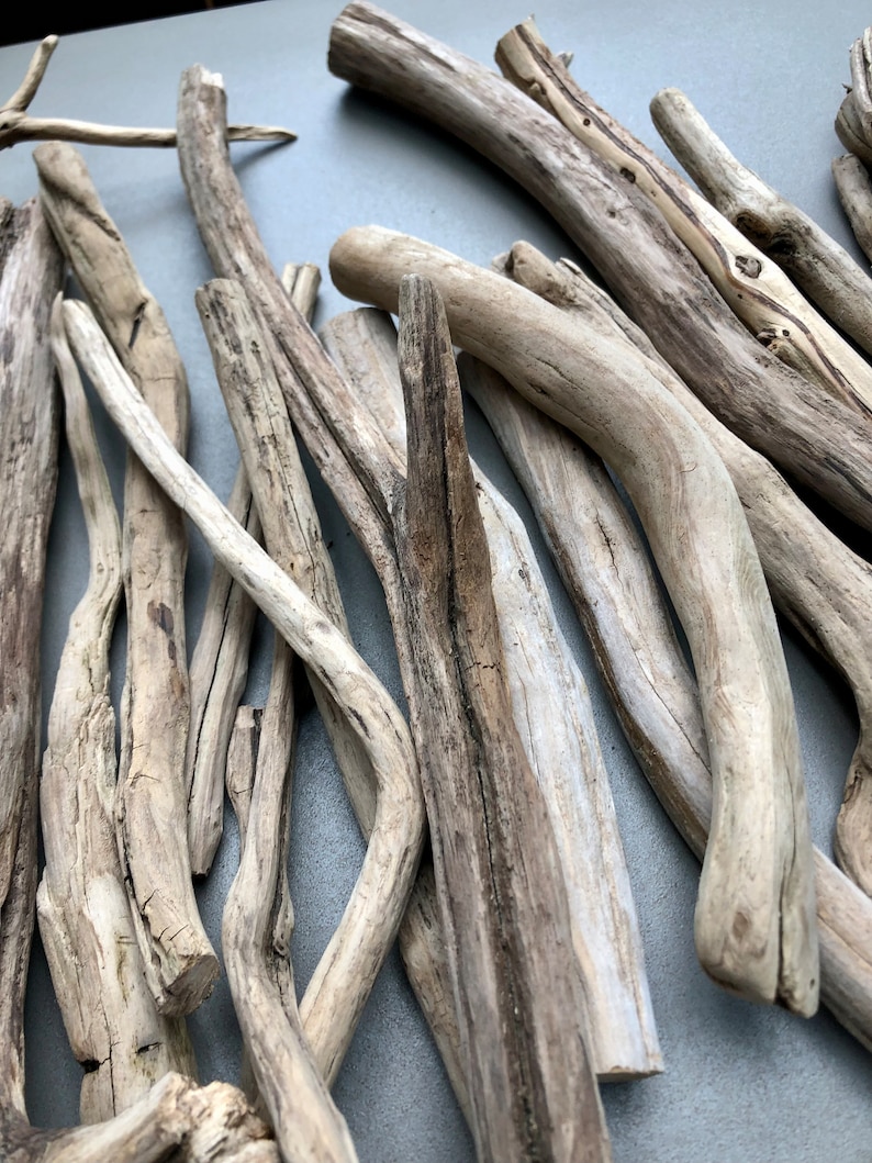 May include: A collection of driftwood sticks in various sizes and shapes, with a light brown and gray color. The sticks are arranged in a random pattern, creating a natural and rustic aesthetic.