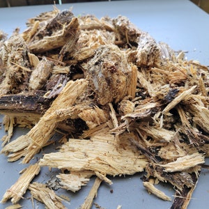 May include: A pile of wood chips and small pieces of wood, some of which are brown and some of which are light brown.