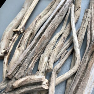 May include: A collection of driftwood sticks in various sizes and shapes, with a natural gray and brown color. The sticks are arranged in a random pattern, creating a rustic and organic aesthetic.