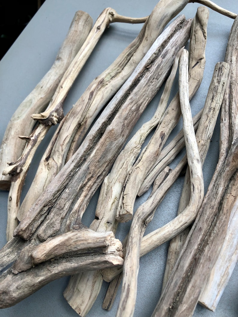 May include: A collection of driftwood sticks in various sizes and shapes, with a natural gray and brown color. The sticks are arranged in a random pattern, creating a rustic and organic aesthetic.