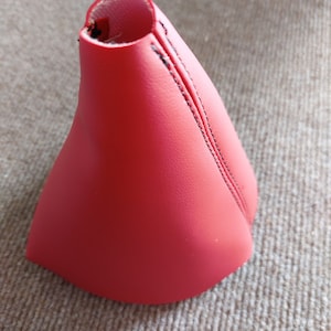 Op de afbeelding: Rode leren versnellingspookhoes met zwarte stiksels.