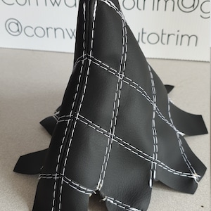 May include: Black leather gear shift boot with white stitching in a diamond pattern.