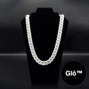 Könnte beinhalten: Eine weiße, klobige Kettenhalskette, die auf einem schwarzen Schmuckständer ausgestellt ist. Die Halskette hat ein kühnes, verbundenes Design. Der Hintergrund ist schwarz, und ein schwarzer Kreis mit dem Text "Glo™" befindet sich in der unteren rechten Ecke.